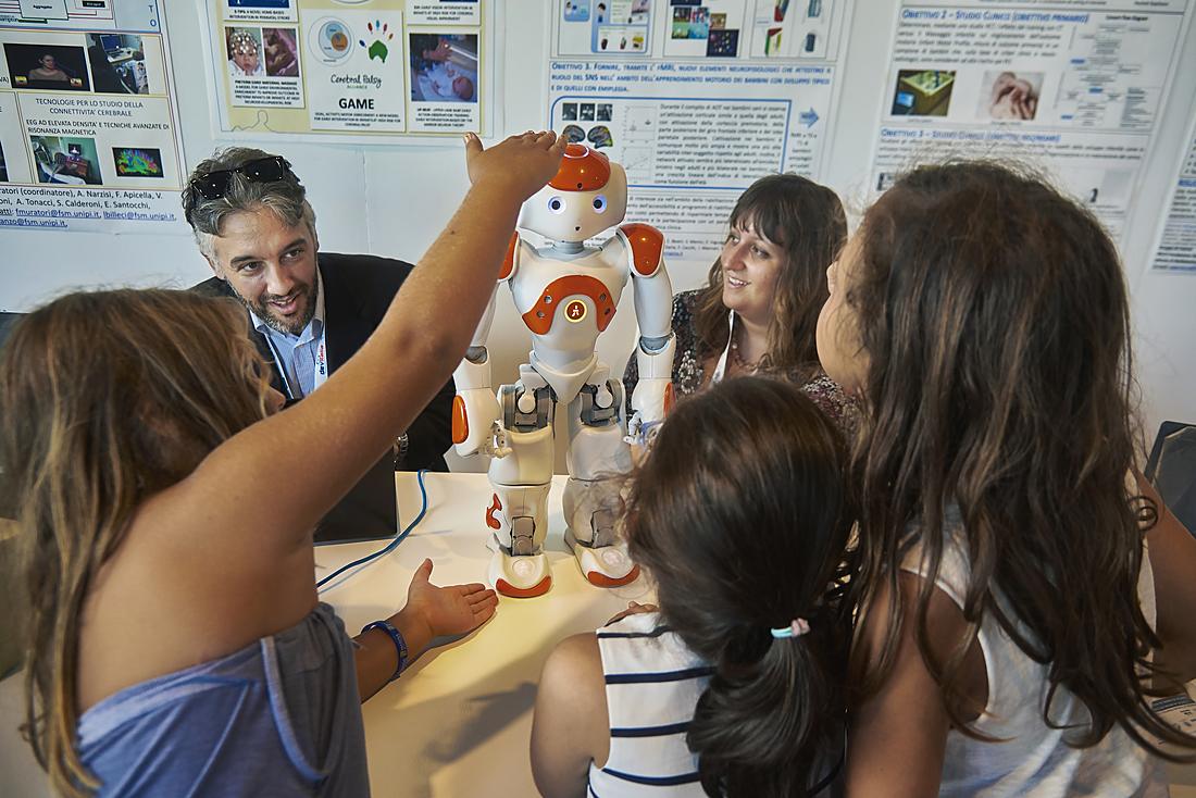 Bambini e un ricercatore interagiscono con il robot umanoide NAO al Festival della Robotica: un esempio di robotica assistiva ed educativa per la disabilità.