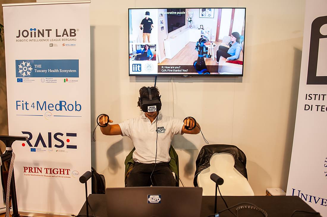 Una persona con visore di realtà virtuale durante una sessione di riabilitazione robotica in un laboratorio di ricerca.